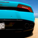 The rear of a turquoise Lamborghini on a beach, its license plate reading Z000000M.